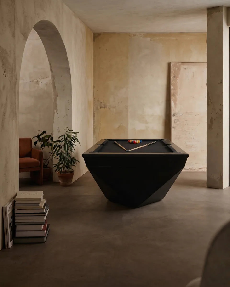 Billard noir aux flancs facettés, dans une pièce aux murs patinés et à l'arche
