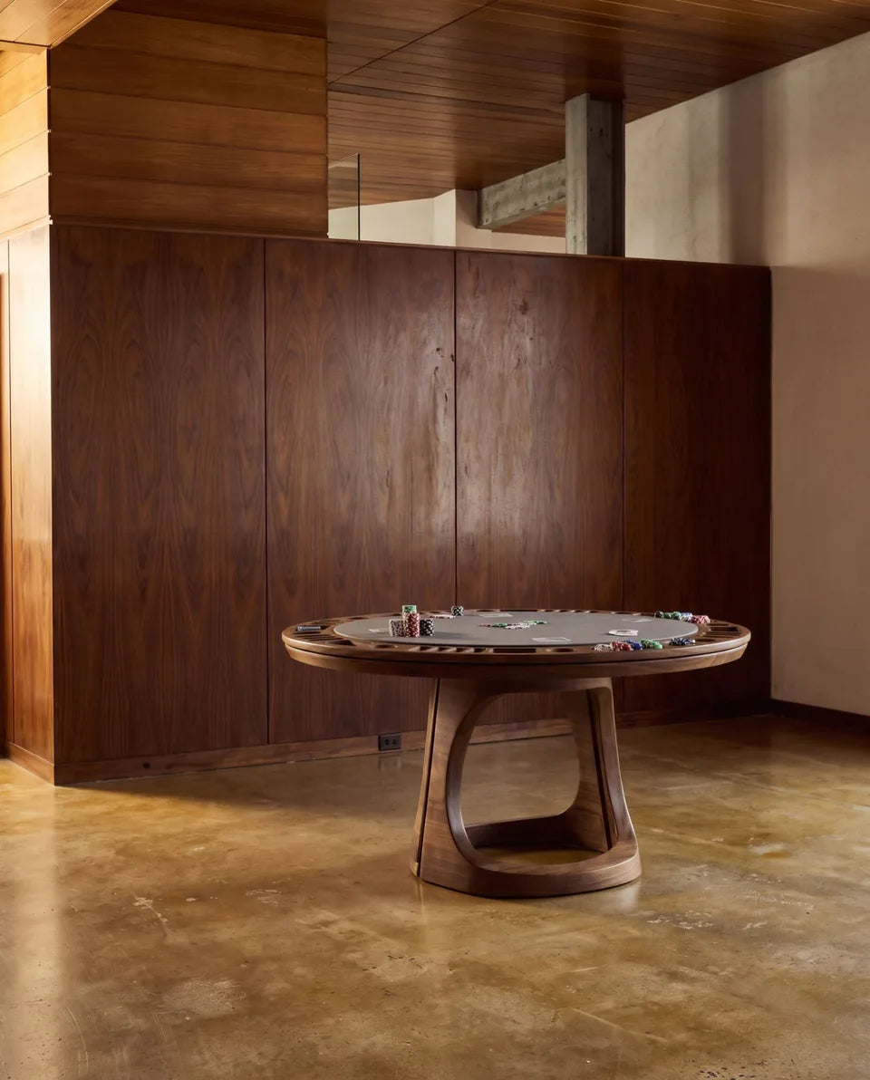 Table de poker ronde en bois foncé devant un mur lambrissé, sol en béton ciré ocre