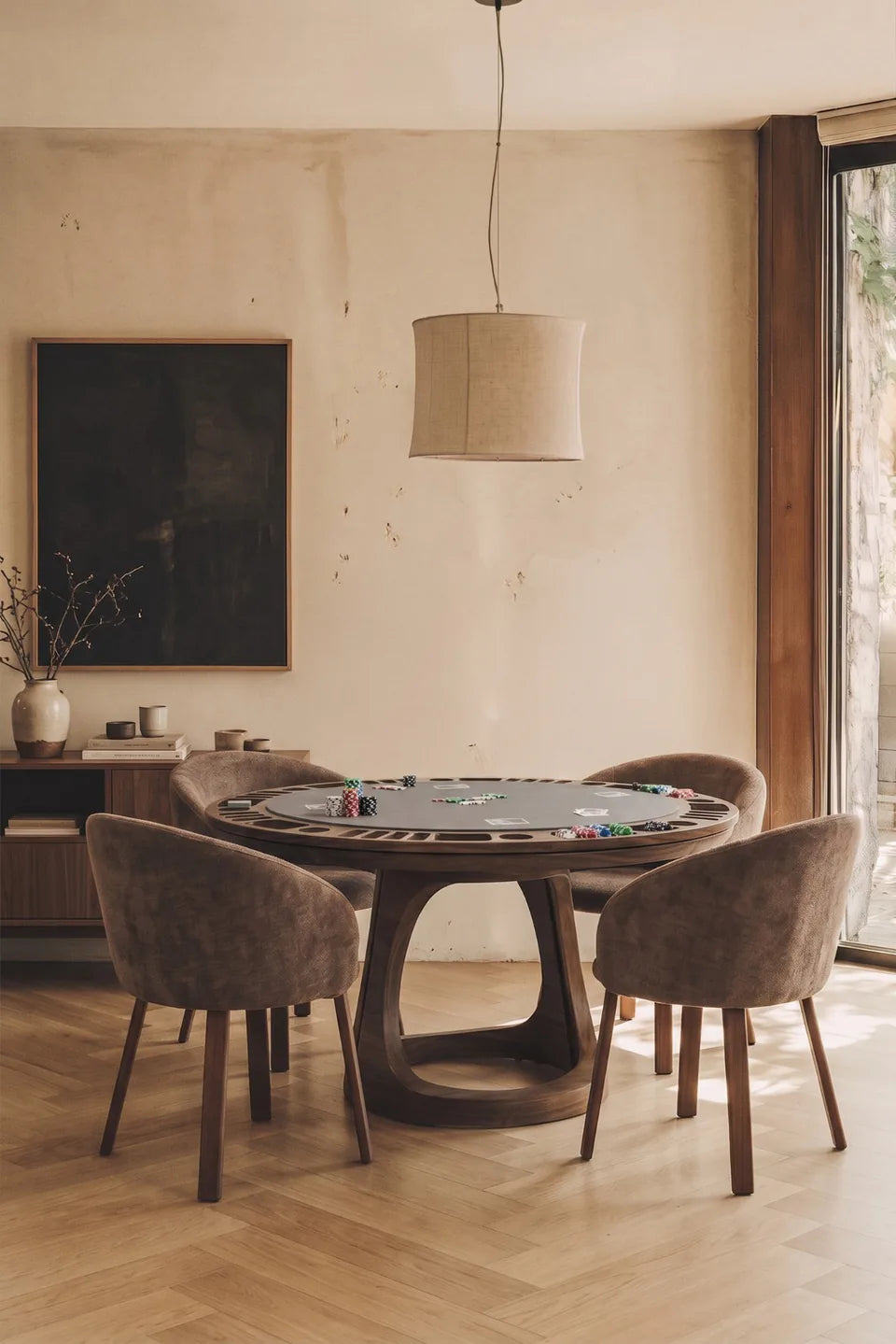 Table de poker ronde en bois foncé entourée de quatre fauteuils en velours taupe, parquet à chevrons